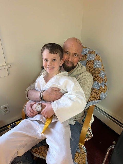Brian Kreizinger, an art teacher at Taunton High School who died of cancer on April 17, 2025, holds his son, Oliver.