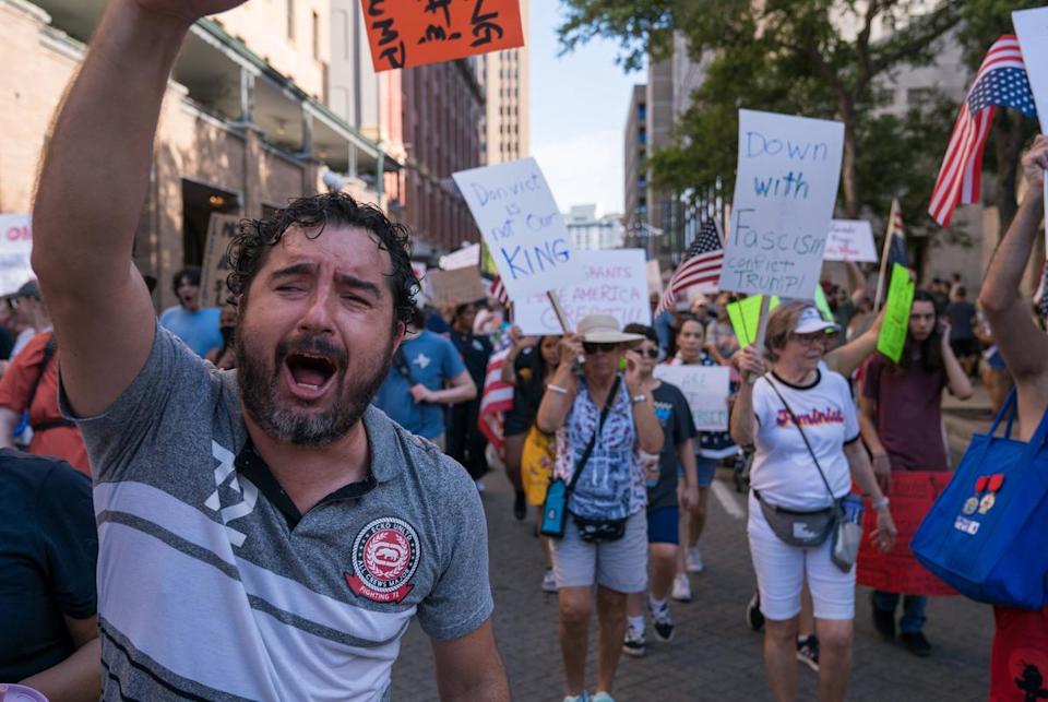 A protester raises a sign reading "NO KING #2025" while chanting as demonstrators march through the streets of downtown San Antonio on June 14, 2025 in San Antonio, Texas. The protest was part of nationwide demonstrations against Trump administration immigration policies.