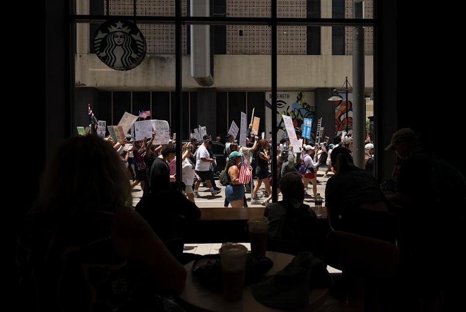 People watch the No Kings protest from a Starbucks on Saturday, June 14, 2025, in Dallas, Texas. The No Kings Day of Defiance was projected to be the largest single-day mobilization since Trump returned to office.