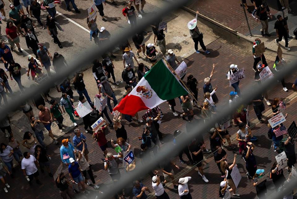 A protestor carries the Mexican flag as people march up Walker Street during a No Kings protest at City Hall, Saturday, June 14, 2025, in Houston. (Antranik Tavitian for The Texas Tribune)