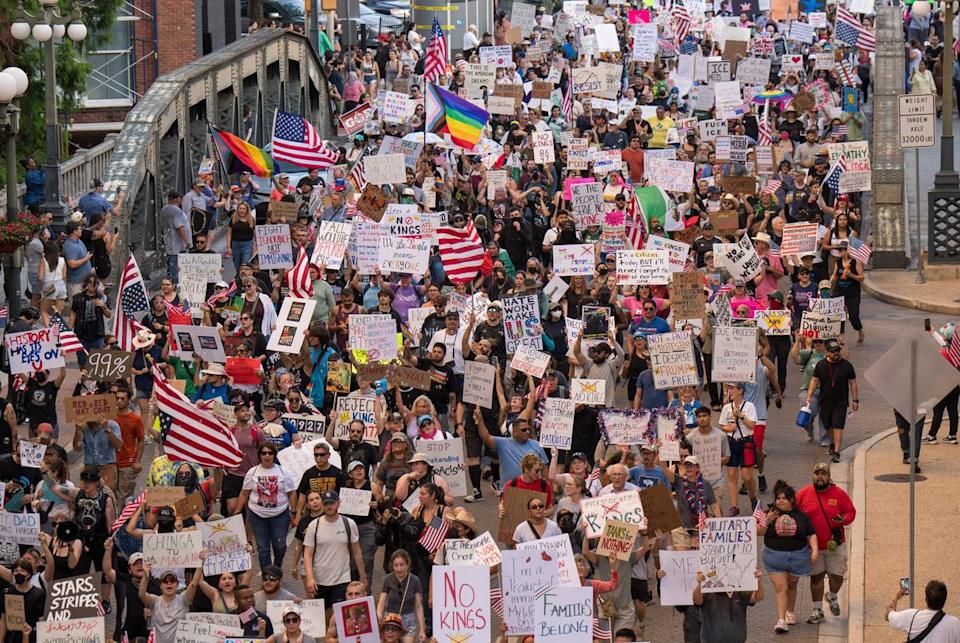 Hundreds of protesters march down Navarro Street carrying signs and American flags during the "No Kings" demonstration on June 14, 2025 in downtown San Antonio, Texas. The protest was part of nationwide demonstrations against Trump administration immigration policies.