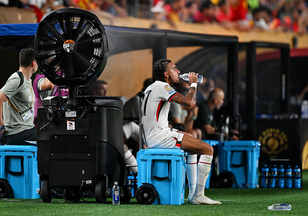 Malo Gusto of Chelsea FC drinks water while being cooled by a misting fan during the FIFA Club World Cup 2025 in Philadelphia, Pennsylvania.